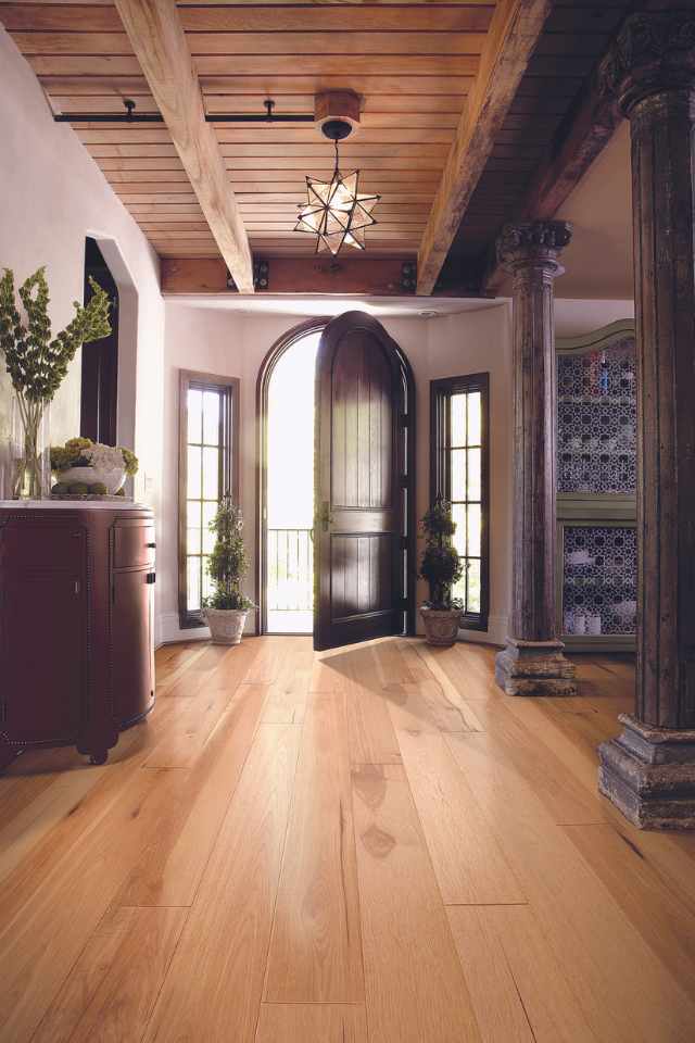 hickory flooring in european farmhouse entryway with carved wood detailing and modern light fixture